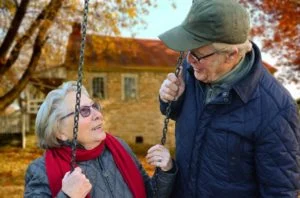 Older couple together outside, lady on a swing 