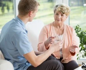 Carer giving elderly lady medication