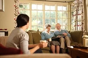 Couple looking through photo album with carer close by