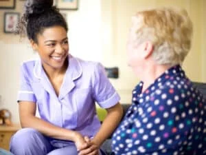 a women working in adult care sitting down with an elderly lady