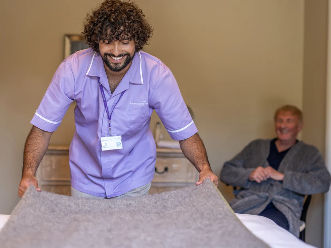 A man in a purple shirt holding a rug.