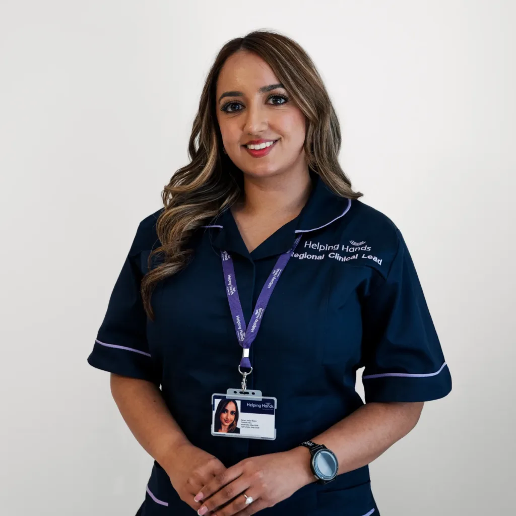 A woman in a navy blue uniform with a name badge and lanyard stands against a white background, smiling with hands clasped.