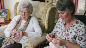 Dorothy knitting with her live-in carer, Magda