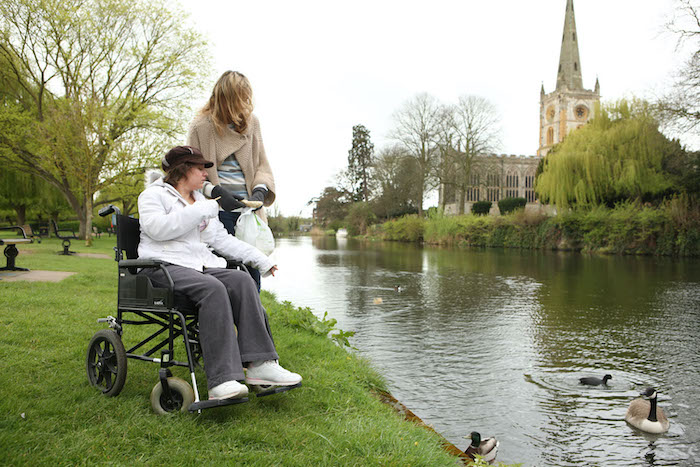 Helping Hands live-in carer feeding ducks with a customer