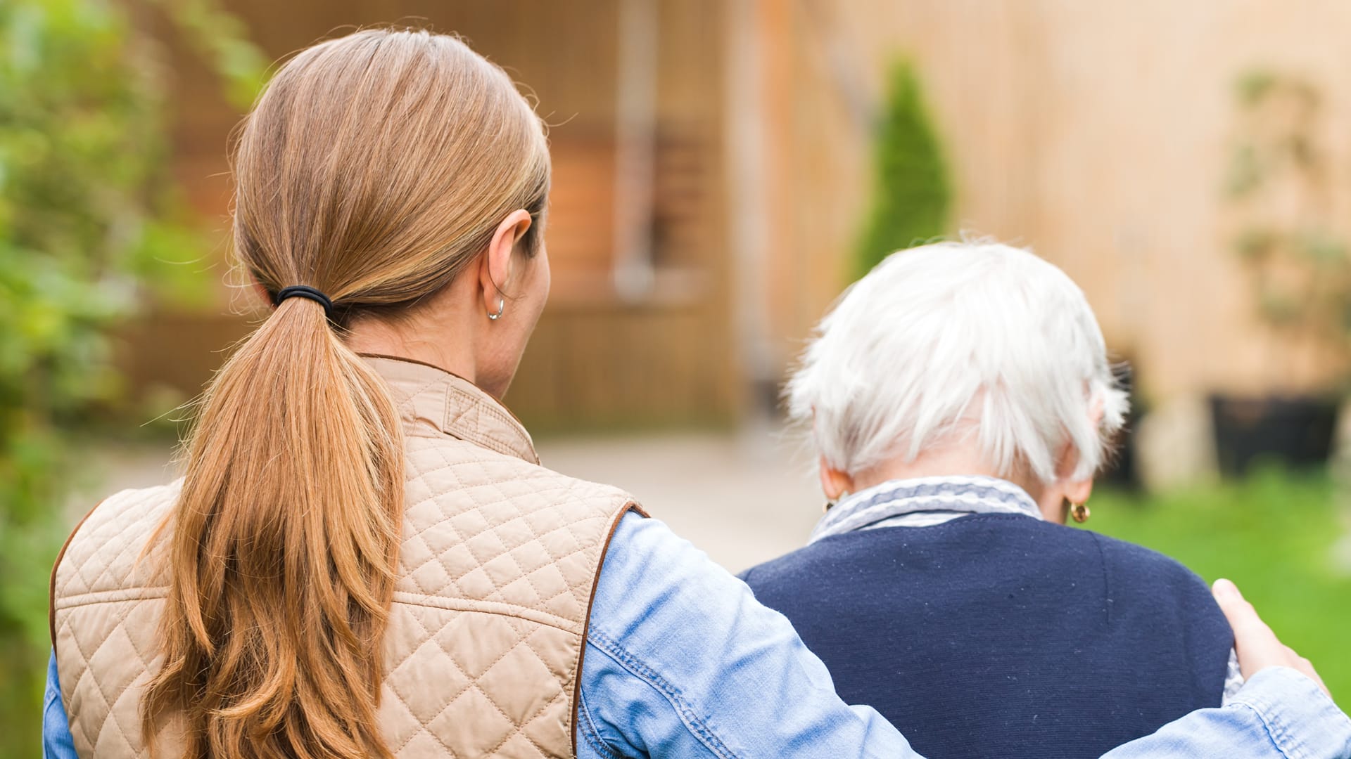 Carer wtih arm around old lady walking forwards