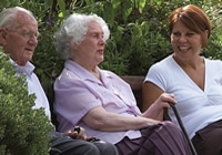 An elderly couple in their garden with their live-in carer