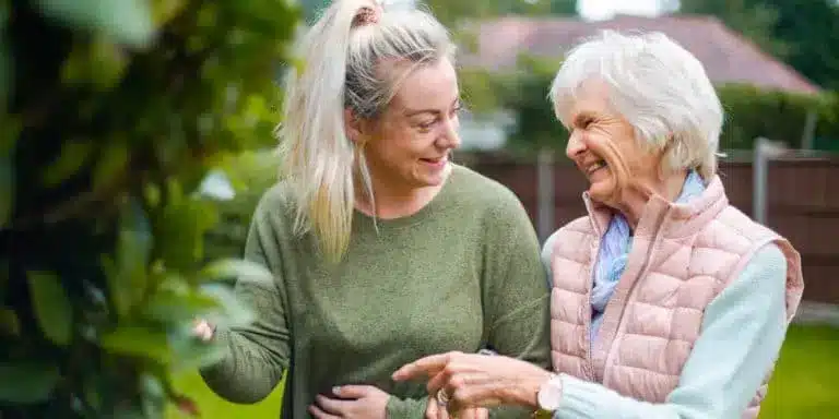 International carer helping elderly lady around the garden